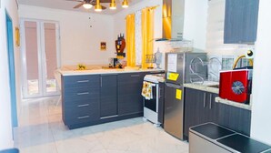 A modern kitchen with dark cabinetry, a stainless steel refrigerator, a built-in oven, and a red dishwasher.
