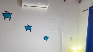 A bedroom with a bed, a nightstand, a lamp, and decorative sea turtle wall art. - Lovely villa with AC in Playa Potrero, Guanacaste. Enjoy nature and the beach (Playa Potrero, Santa Cruz)