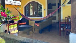 A covered outdoor seating area with a hammock, chairs, and a grill. - Lovely villa with AC in Playa Potrero, Guanacaste. Enjoy nature and the beach (Playa Potrero, Santa Cruz)