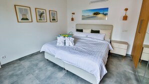 A modern bedroom with a bed, bedside tables, and artwork on the walls.