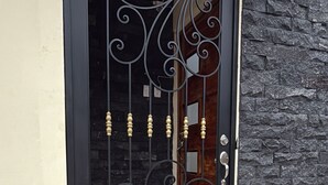 Uma porta preta com detalhes em metal e uma parede de pedra.