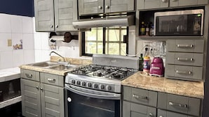 Uma cozinha com armários cinza, fogão a gás, micro-ondas e liquidificador.