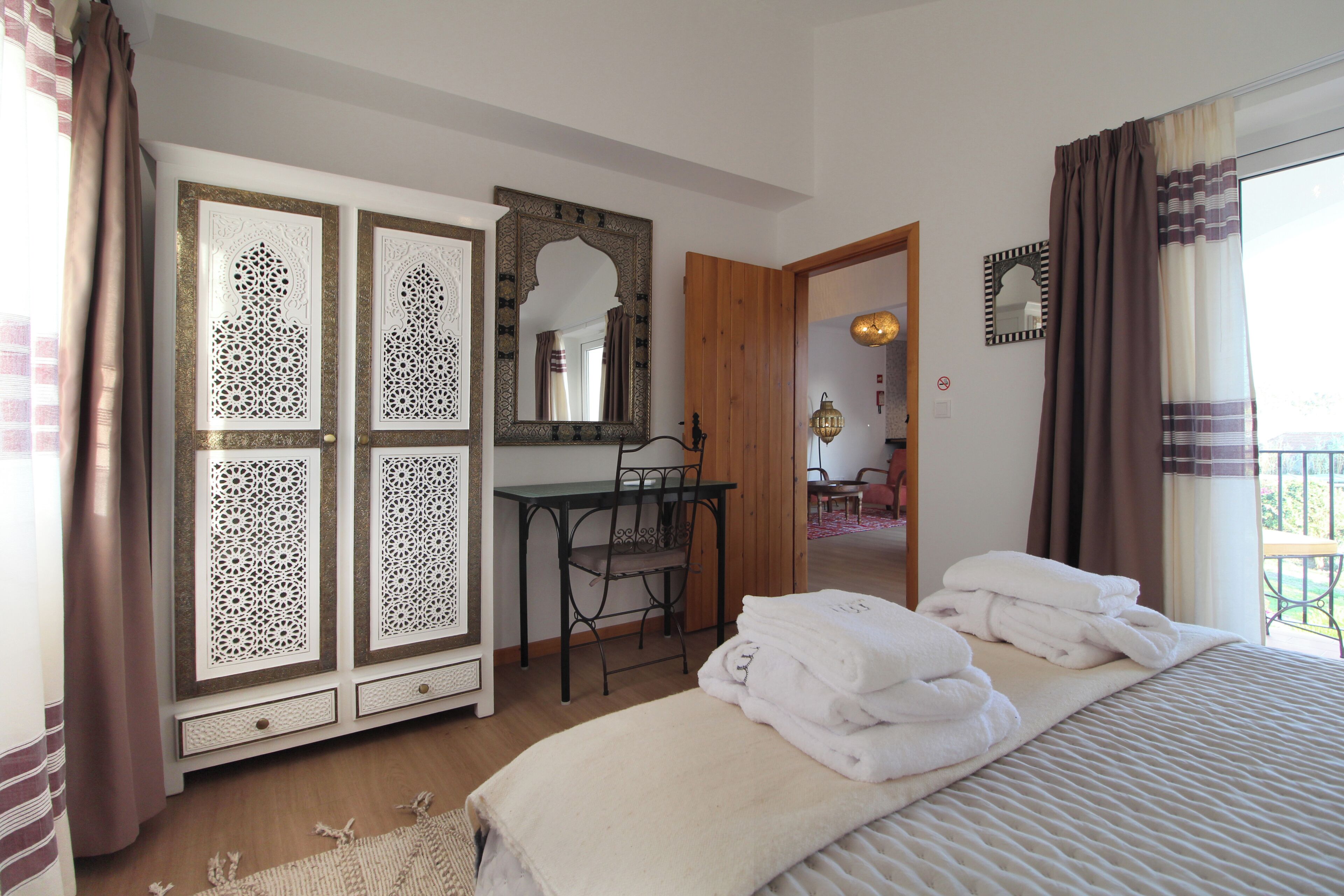 Une chambre à coucher avec un lit, un bureau et une chaise. Des serviettes sont pliées et empilées sur le lit.