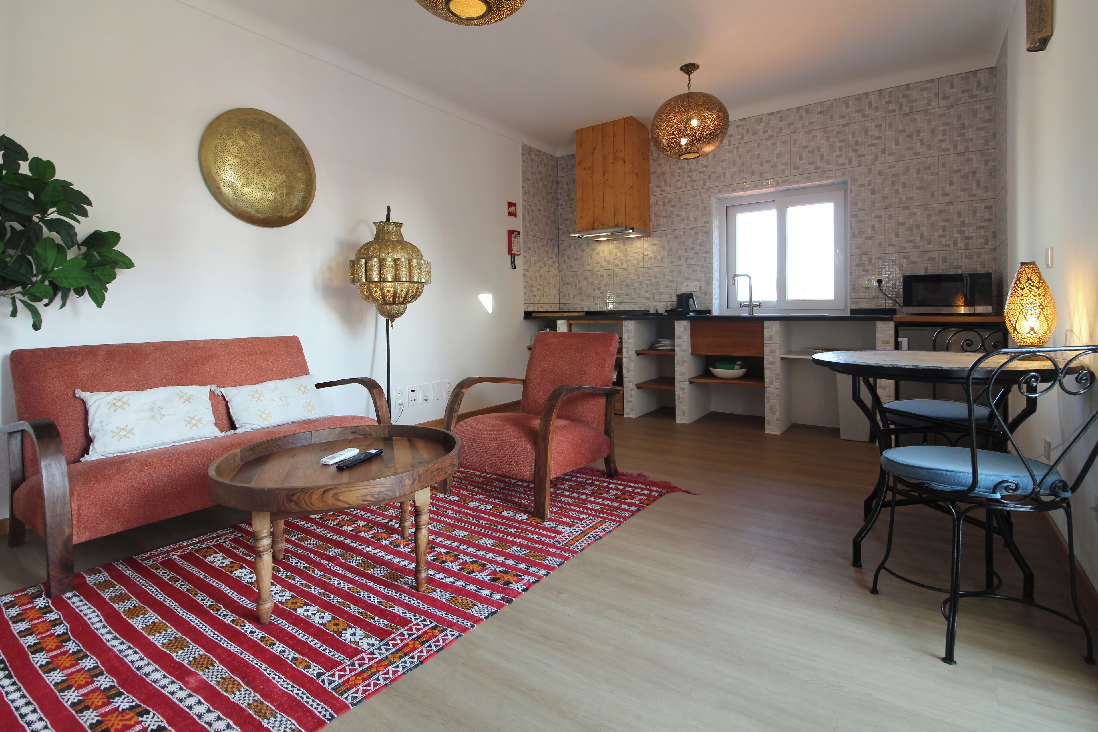 Un espacio habitable pequeño con sofá, sillón, mesa de comedor y zona de cocina.