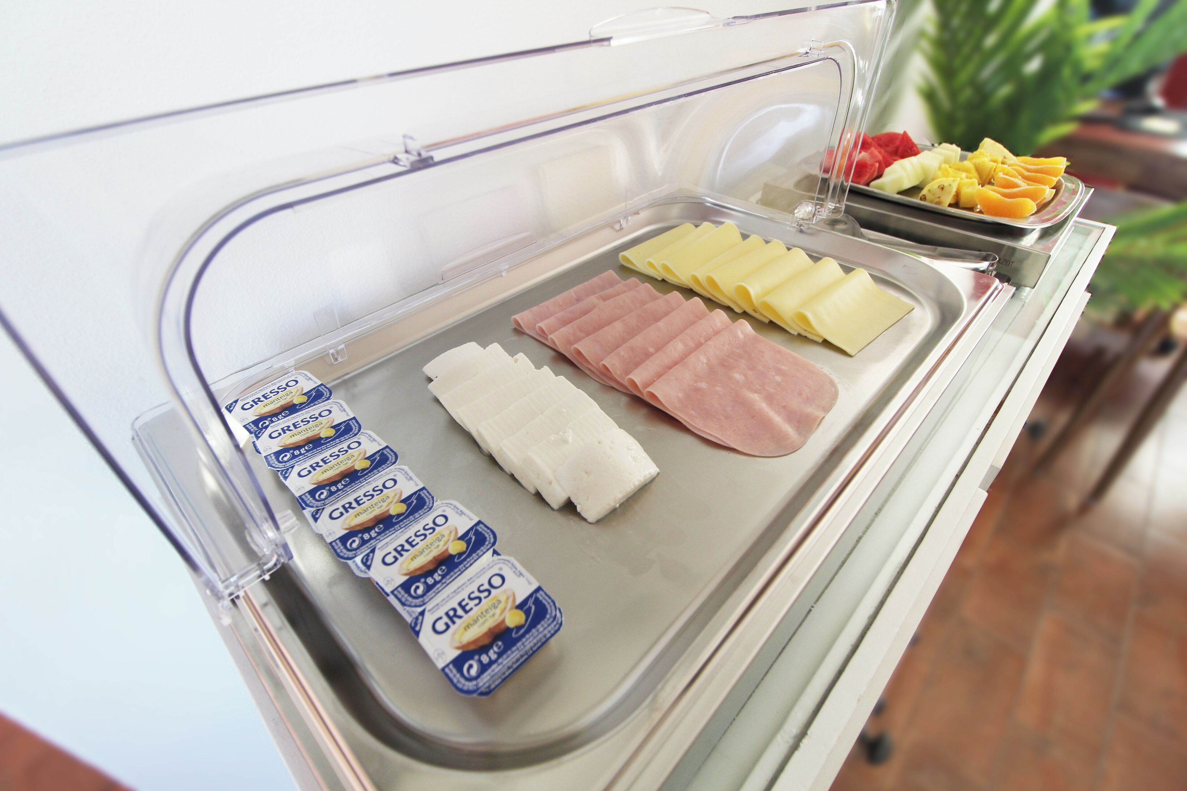 Ein Buffet mit verschiedenen Speisen, darunter Käse, Schinken und Früchte.