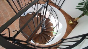 A spiral staircase with a metal railing, wooden steps, and a potted plant on the landing. - Quinta do Canal (Odemira)
