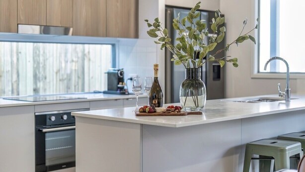 Een moderne keuken met een centraal eiland, roestvrijstalen apparatuur en uitzicht op de omgeving.