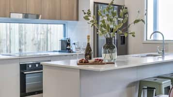 A modern kitchen with a central island, stainless steel appliances, and a view of the outdoors.