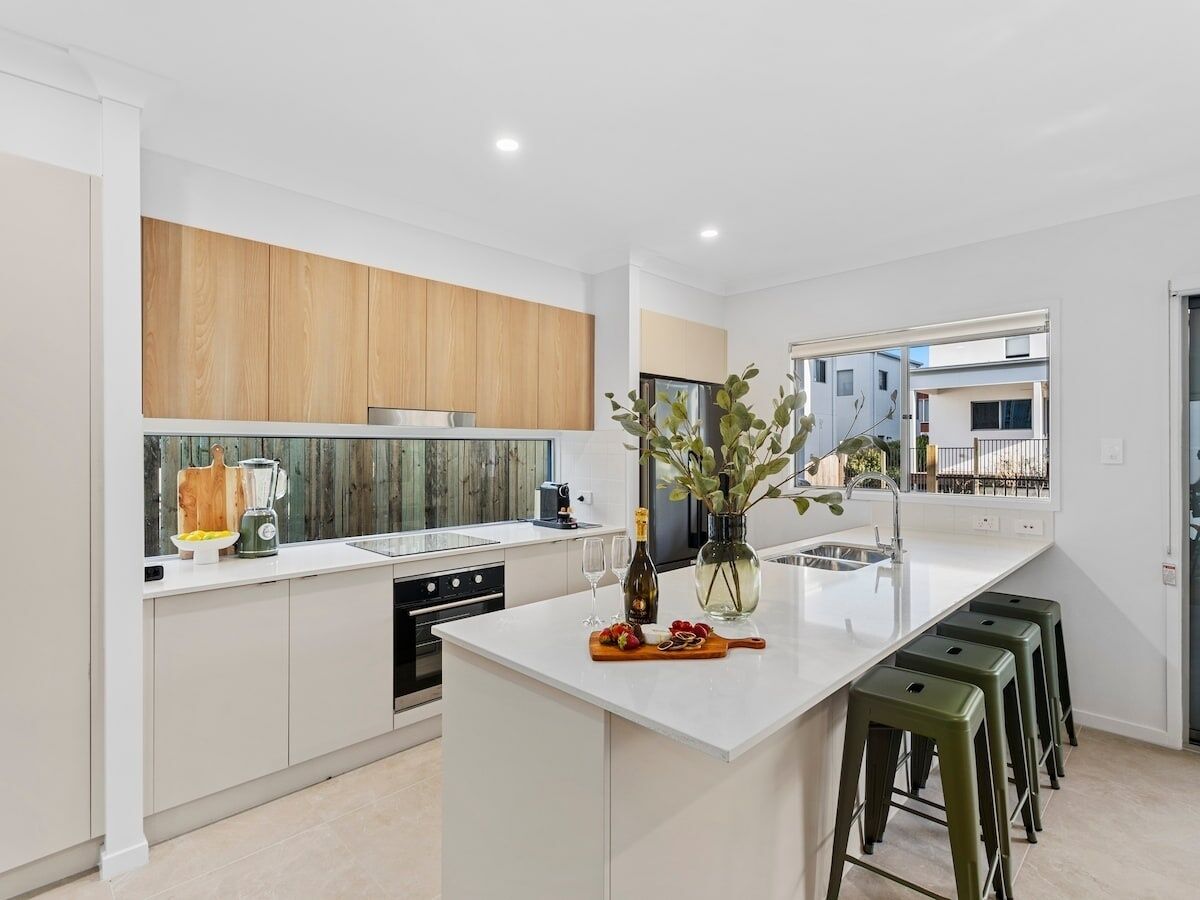 A modern kitchen with white cabinetry, a central island, and bar stools.