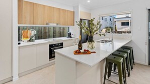 Een moderne keuken met witte kasten, een centraal eiland en barkrukken.