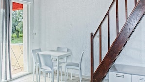 A room with a white table and chairs, a wooden staircase, and a door leading to an outdoor area. - Res. Marea Resort, Santa-lucia-di-moriani (Santa-Lucia-di-Moriani)