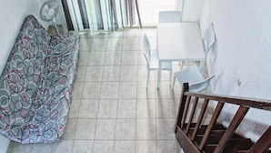 A small, enclosed patio with a white table and chairs, a patterned sofa, and a fan. - Res. Marea Resort, Santa-lucia-di-moriani (Santa-Lucia-di-Moriani)