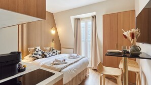 Ein modernes Hotelzimmer mit Bett, Schreibtisch, Stuhl, Fernseher und einem Fenster mit Vorhängen.
