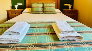 A neatly made bed with a striped bedspread, two pillows, and folded towels on either side.