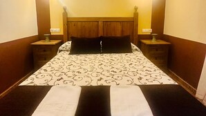 A hotel room with a bed, two bedside tables, and two wall-mounted lamps.