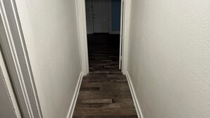 Un pasillo estrecho con paredes blancas y suelo de madera.