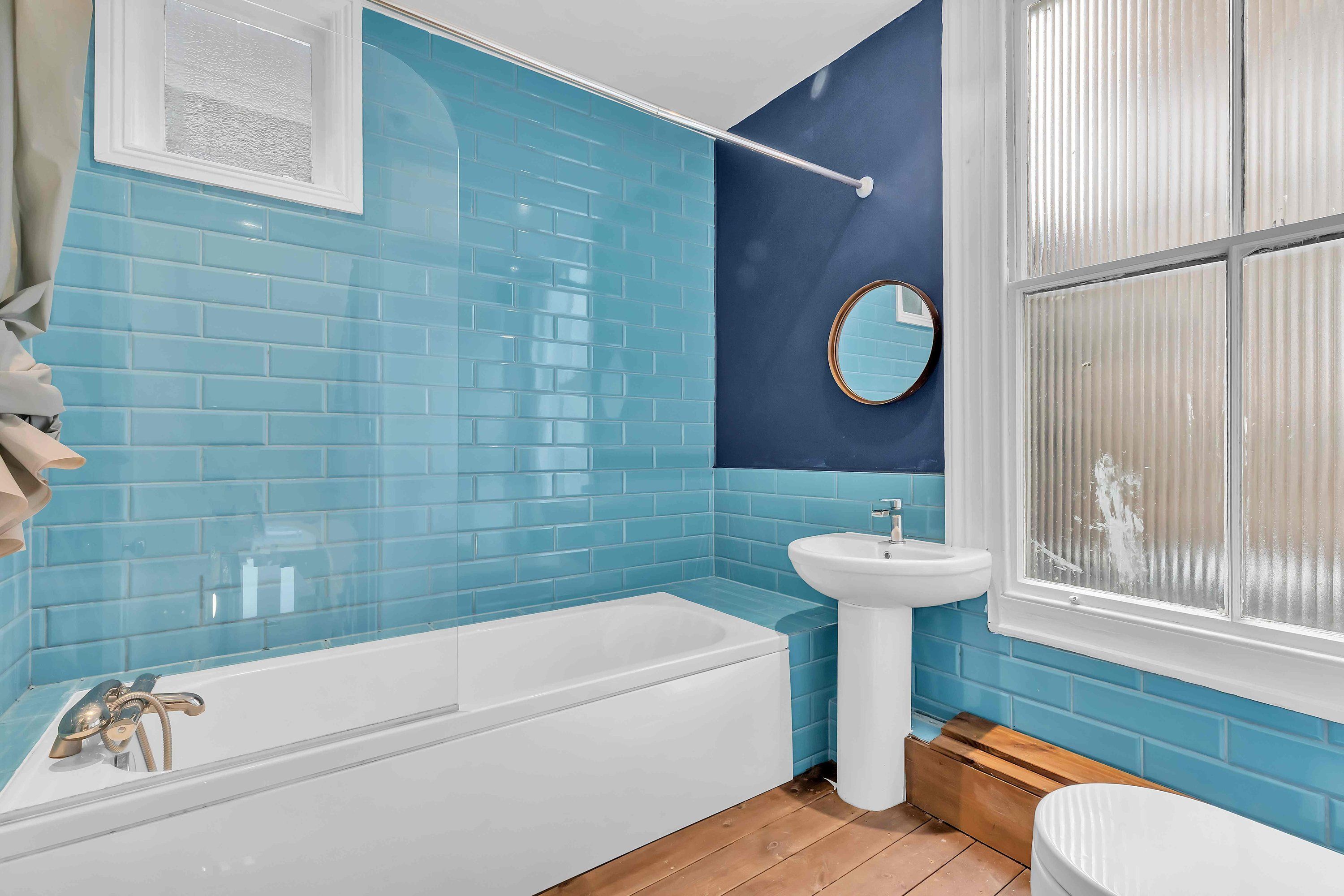 A bathroom with a bathtub, a sink, and a window.