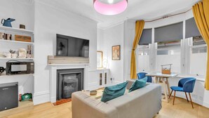 Un salon moderne avec une cheminée, un canapé, un téléviseur et un coin repas.