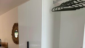 A room with a white wardrobe, a wooden floor, and a wall-mounted drying rack. - Ce logement vous accueille à 25mn des plages des sites du D-DAY et de ses plages (Balleroy-sur-Drôme)