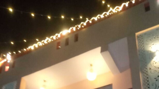 Un edificio de dos pisos con un balcón en el nivel superior, una puerta en la planta baja y luces colgantes en el techo.