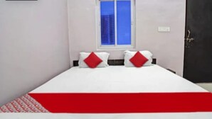 Un dormitorio con una cama, dos almohadas, una ventana y una puerta.