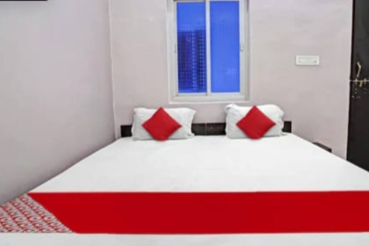 Quarto com cama, duas almofadas, janela e porta.