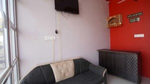 Una habitación con un sofá, una mesita, una pared roja y una ventana.
