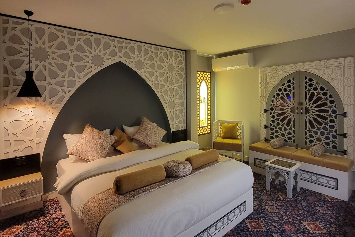 Ein Schlafzimmer mit einem großen Bett, einer Bank und einem gemusterten Teppich.