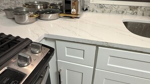A kitchen with a gas stove, a toaster, and various pots and pans on the counter.