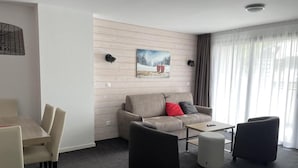 A modern hotel room with a sofa, two armchairs, a small table, and a dining area. - 150m from ski slopes, 2nd floor, swimming pool, tv, ski locker, 57m², Gourette (Eaux-Bonnes)