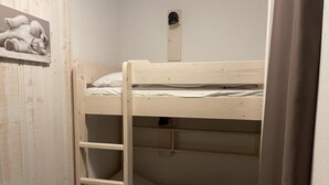 En køjeseng med en stige, en lille hylde og en vægmonteret hylde med et billede.