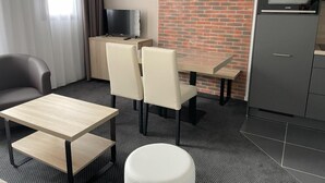 Een moderne hotelkamer met een zithoek, een televisie en een kitchenette.