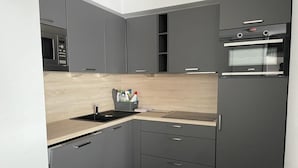 A modern kitchen with grey cabinets, a microwave, a sink, and a built-in oven.