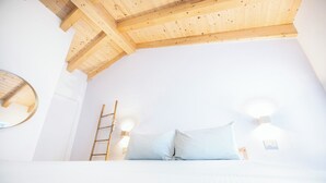 A bedroom with a wooden ceiling, a ladder, two bedside lamps, and a round mirror on the wall. - B&B La Volpe (Moneglia)
