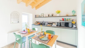 A bright kitchen with a wooden ceiling, a dining table with chairs, a microwave, and various kitchen items on the counter. - B&B La Volpe (Moneglia)