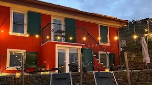 A red building with a balcony and two lounge chairs in front. - B&B La Volpe (Moneglia)
