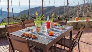 An outdoor dining table with chairs, a bottle, and a glass of red juice. - B&B La Volpe (Moneglia)