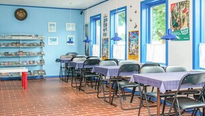 A room with blue walls, multiple tables with chairs, and shelves with books. - 4 Person Holiday Park Home in Grindsted (Grindsted)
