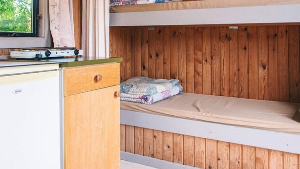 A bunk bed with a wooden wall and a window. There is a small white appliance on the left. - 4 Person Holiday Park Home in Grindsted (Grindsted)