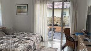 Ein Schlafzimmer mit Bett, Schreibtisch, Stuhl und Blick ins Freie.