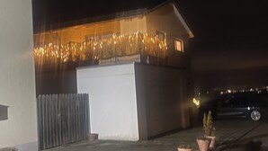 Ein Gebäude mit weißer Fassade, einem Holzzaun und einem Auto auf der Auffahrt.