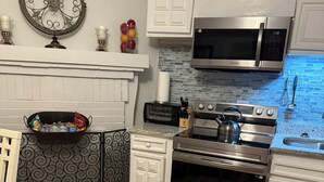 Una cucina moderna con mobili bianchi, un piano cottura in acciaio inossidabile, un forno a microonde e un tostapane.