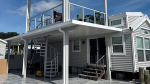 A two-story house with a covered balcony and a staircase leading to the upper level. - Delightful Tiny home with amazing views in Key Largo (Key Largo)