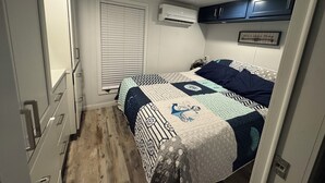 A bedroom with a bed, a window with blinds, a wall-mounted air conditioner, and a small framed picture. - Delightful Tiny home with amazing views in Key Largo (Key Largo)