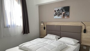 A neatly made bed with a white comforter and pillows, a headboard with a light wood finish, and a wall-mounted artwork above. - 80m from resort center, 3rd floor, swimming pool, terrace, tv, ski locker, 57m², Gourette (Eaux-Bonnes)