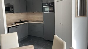 A compact kitchen with grey cabinets, a microwave, an oven, and a sink. - 80m from resort center, 3rd floor, swimming pool, terrace, tv, ski locker, 57m², Gourette (Eaux-Bonnes)