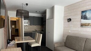 Un espacio habitable compacto con kitchenette, comedor y sofá.