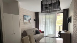 Una habitación de hotel moderna con un sofá, una mesa de vidrio y un televisor montado en la pared.