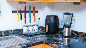 Een keuken met een marmeren aanrecht, een koffiezetapparaat, een blender en keukengerei aan de wand.
