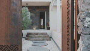 A pathway leading to a stone entrance with a door, surrounded by white pebbles and steps. - Al Borgo Luxury suite 01 (Abbasanta)